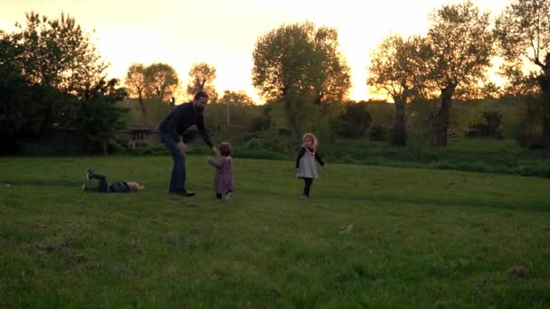 Gente en el parque. silueta familiar feliz al atardecer. Papá balanceo bebé por hte manos han pasado tiempo. padres y niños divertidos caminando al aire libre al aire libre. Día del padre, infancia, concepto de paternidad — Vídeos de Stock