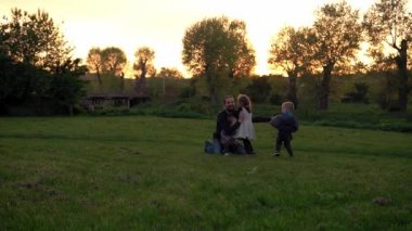 people in the park. happy family silhouette at sunset. children run to dad arms fall have spend time. parents and fun children walking outdoors in open air. Fathers day, childhood, parenthood concept