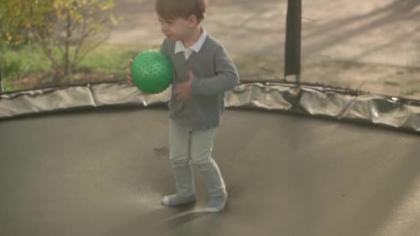 Spring, sport, holyday, family, childhood - Slow motion Two happy little toddler preschool siblings Children twins kids play have fun jumping balls on trampoline outside sunny evening sunset in park. — Stock Video