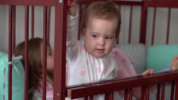 Mignon joyeux 3 petits enfants fille et garçon frères et sœurs enfants d'âge préscolaire dans la crèche de bébé gris après s'être réveillé du sommeil en pyjama avec les jambes pendantes. Enfance, loisirs, confort, médecine, concept de santé — Video