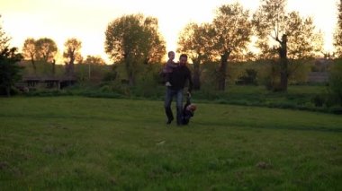 Parktaki insanlar. Gün batımında mutlu aile silueti. Baba ve bebek el ele tutuşarak zaman geçirdiler. Aileler ve eğlenceli çocuklar açık havada yürüyorlar. Babalar Günü, çocukluk, ebeveynlik kavramı.