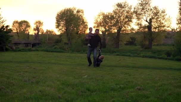 Menschen im Park. glückliche Familiensilhouette bei Sonnenuntergang. Händchenhaltend haben Vater und Baby die Zeit verbracht. Eltern und lustige Kinder, die im Freien spazieren gehen. Vatertag, Kindheit, Elternschaft — Stockvideo