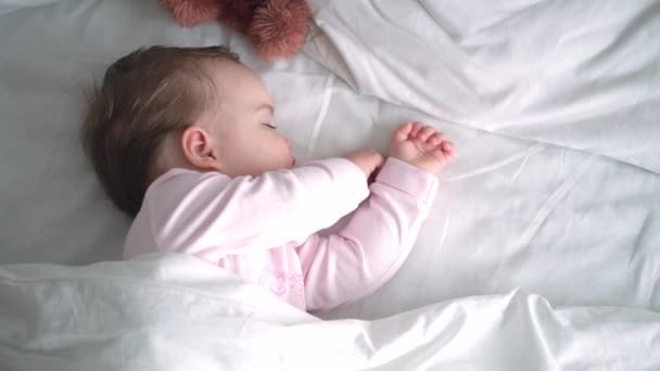 Autentico ritratto carino caucasico neonato paffuto bambina o ragazzo nel sonno rosa con orsacchiotto sul letto bianco. bambino che riposa all'ora di pranzo. cura, Bambino che dorme, Infanzia, Genitorialità, concetto di vita — Video Stock