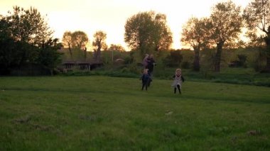 Parktaki insanlar. Gün batımında mutlu aile silueti. Baba ve bebek el ele tutuşarak zaman geçirdiler. Aileler ve eğlenceli çocuklar açık havada yürüyorlar. Babalar Günü, çocukluk, ebeveynlik kavramı.