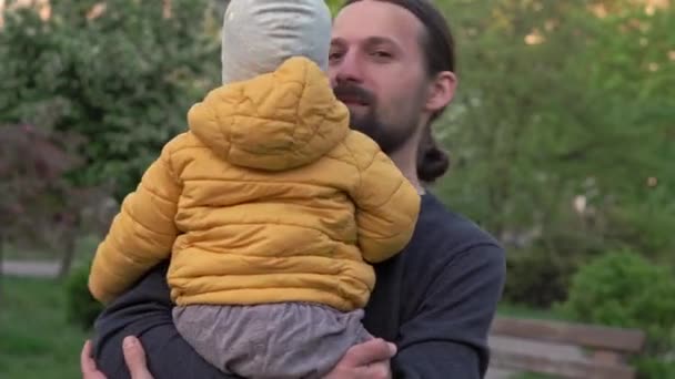 公园里的人爸爸把女婴抱在怀里，挠痒痒的感觉也很强烈。父母和孩子们在户外散步的乐趣。父亲节、快乐的家庭、童年、养育子女的观念 — 图库视频影像