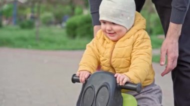 Parktaki insanlar. Baba, küçük kızı motorsiklete bindirip gezdirmiş ve gezdirmiş. Aileler ve eğlenceli çocuklar açık havada yürüyorlar. Babalar Günü, mutlu aile, çocukluk, ebeveynlik kavramı.