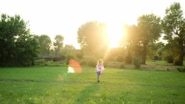 Verano, vacaciones, naturaleza, familia feliz, niñez un pequeño niño bastante pequeño preescolar bebé niña correr jugar divertirse con gran bola inflable captura en el parque en la hierba al atardecer al aire libre — Vídeos de Stock