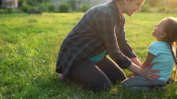 Summer, nature, happy family, pregnancy - young pregnant woman mother with two small toddler children sit on grass in park at sunset. Kids stroking mom belly kiss have fun, laugh spend time together — Stock Video