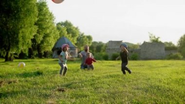 Yaz, tatil, doğa, mutlu aile, çocukluk, babalık, baba günü - Küçük bir anaokulu çocuğu olan baba - Çocuklar koşuyor çocuklar gün batımında parkta büyük şişme topla oynarken eğleniyorlar