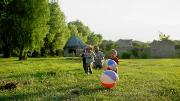 Yaz, tatil, doğa, mutlu aile, çocukluk, babalık, baba günü - Küçük bir anaokulu çocuğu olan baba - Çocuklar koşuyor çocuklar gün batımında parkta büyük şişme topla oynarken eğleniyorlar — Stok video