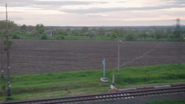 View from window of high-speed train on landscape of beautiful nature field village houses and forest on evening dusk sky sunset in summer background. Transport, travel, railway, communication concept — Stock Video