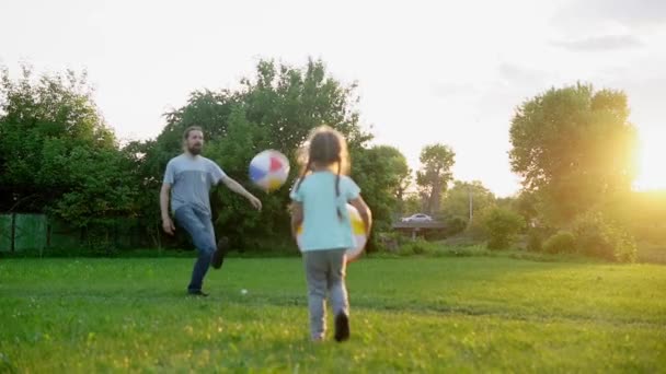 Verano, vacaciones, naturaleza, familia feliz, infancia, paternidad, día del padre papá con los niños pequeños del preescolar corren divertirse jugando al fútbol con la bola inflable grande en el parque al atardecer — Vídeos de Stock
