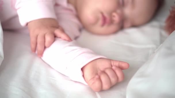 확실 한 초상화귀여운 코카서스의 작은 아기가 분홍색 침대에 테디베어 와 함께 잠을 자고 있거나 남자 아이가 흰색 침대에 누워 있다. 아이는 점심 시간에 쉬고 있습니다. 보육, 잠자는 아이, 어린 시절, 부모로서의 삶의 개념 — 비디오