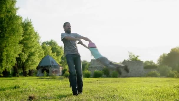 Verano, vacaciones, naturaleza, familia feliz, infancia, paternidad, día del padre papá con los niños pequeños del preescolar los niños del bebé funcionan juegan se divierten balanceando por las manos con la bola inflable grande en el parque al atardecer — Vídeos de Stock