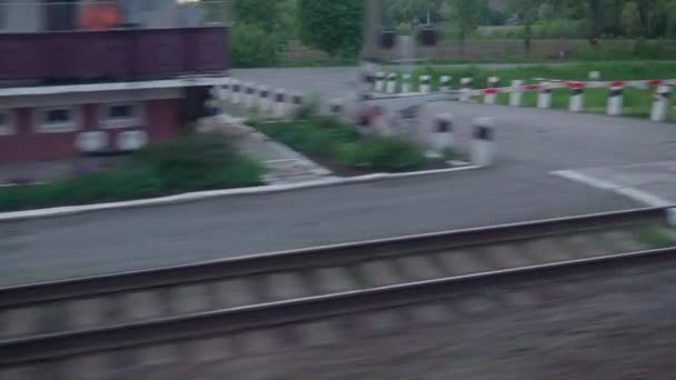 View from window of speed train with glare on glass and parallel rails on landscape of meadows and forest before sunset in summer background. Transport, travel, road, railway, comnication concept — Stock Video