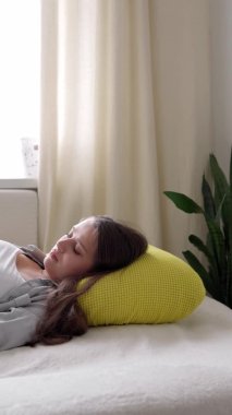 Yorgun, karnına dokunan hamile bir kadının güneşli bir günde evde yatıp dinlendiği dikey format videosu. hamilelik, annelik, insanlar, beklenti kavramı