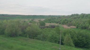 Hızlı trenin camında parlayan ışık ve yaz arkaplanındaki günbatımından önce çayırların ve ormanın manzarasında paralel raylar. Ulaşım, seyahat, yol, demiryolu, zina kavramı