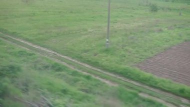 Yüksek hızlı trenin penceresinden güzel doğa manzarası tarla su kulesi rüzgar türbini yaz arka planında akşam alacakaranlık gökyüzü günbatımında. Ulaşım, seyahat, demiryolu, iletişim konsepti