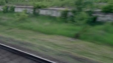 Hızlı trenin camında parlayan ışık ve yaz arkaplanındaki günbatımından önce çayırların ve ormanın manzarasında paralel raylar. Ulaşım, seyahat, yol, demiryolu, zina kavramı