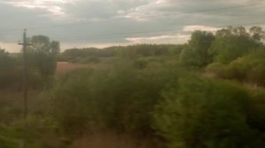 Yüksek hızlı trenin penceresinden manzarası güzel doğa manzarası vahşi arazi ve orman akşam bulutlu gökyüzü günbatımı yaz arkaplanında. Ulaşım, seyahat, demiryolu, iletişim konsepti