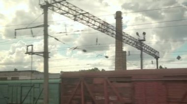 Yüksek hızlı tren penceresinden, paslı vagonların ve yüksek tuğlalı bacaların manzarasından yaz arkaplanındaki bulutlu güzel gökyüzünün manzarasına. Ulaşım, seyahat, demiryolu, yol, zina kavramı