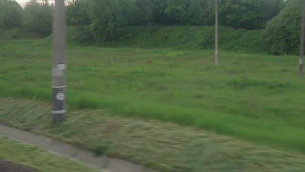 Uitzicht vanaf het raam van de sneltrein met verblinding op glas en parallelle rails op het landschap van weiden en bossen voor zonsondergang in de zomer achtergrond. Vervoer, vervoer, weg, spoor, hoererij — Stockvideo