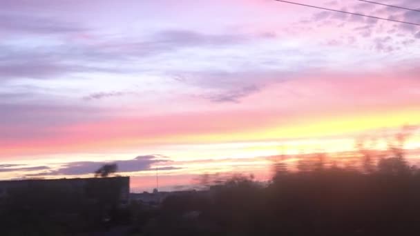 Vista desde la ventana del tren de alta velocidad en el paisaje de la hermosa carretera de campo de la naturaleza con el coche y el bosque atardecer cielo púrpura en el fondo de verano al atardecer. Transporte, viajes, ferrocarril, concepto de comunicación — Vídeo de stock