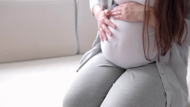 Εγκυμοσύνη, μητρότητα, άνθρωποι, προσδοκία - close up ευτυχισμένη έγκυος γυναίκα αγγίζοντας την κοιλιά της στο κρεβάτι στο σπίτι φροντίδα μητέρα εγκεφαλικά επεισόδια γυμνή μεγάλη κοιλιά με τα χέρια, στο φως δωμάτιο στην ηλιόλουστη μέρα του καλοκαιριού — Αρχείο Βίντεο