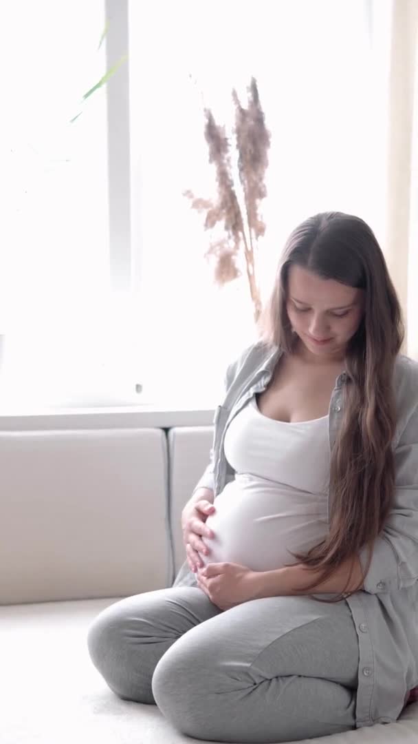 Verticaal Formaat Video van gelukkige zwangere vrouw die thuis buik aanraakt in bed zorgzame moeder streelt grote buik met handen in de zonnige zomerdag. zwangerschap, moederschap, mensen, verwachtingsconcept — Stockvideo