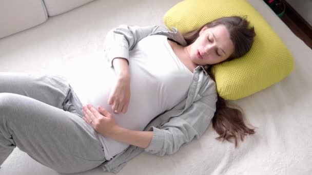 Terhesség, anyaság, emberek, elvárás koncepció - boldog fáradt terhes nő megérinti a pocakját pihenés feküdjön vissza az ágyban otthon gondoskodó anya pihenjen stroke hason fény szoba napsütéses napon — Stock videók