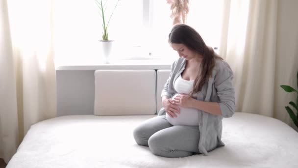 Embarazo, maternidad, personas, concepto de expectativa - mujer embarazada feliz tocando su barriga en la cama en casa caricias madre desnuda barriga grande con las manos, en la habitación de luz en el día de verano soleado — Vídeo de stock