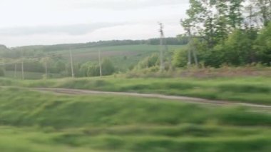 Hızlı trenin camında parlayan ışık ve yaz arkaplanındaki günbatımından önce çayırların ve ormanın manzarasında paralel raylar. Ulaşım, seyahat, yol, demiryolu, zina kavramı