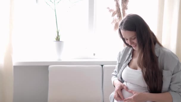 Εγκυμοσύνη, μητρότητα, άνθρωποι, προσδοκία έννοια - ευτυχισμένη έγκυος γυναίκα αγγίζοντας την κοιλιά της στο κρεβάτι στο σπίτι φροντίδα μητέρα εγκεφαλικά επεισόδια γυμνή μεγάλη κοιλιά με τα χέρια, στο φως δωμάτιο στην ηλιόλουστη μέρα του καλοκαιριού — Αρχείο Βίντεο