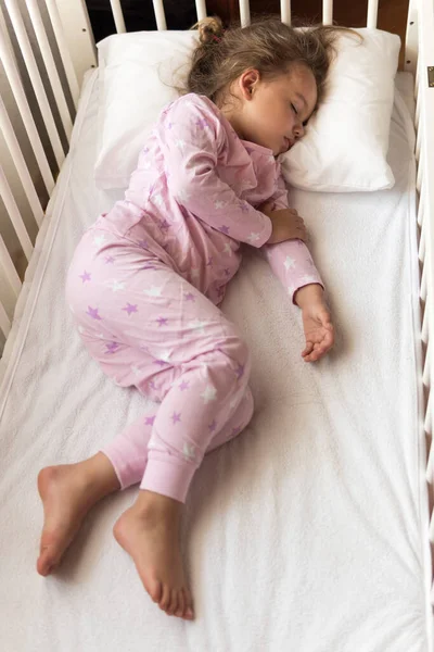 Bovenaanzicht Schattig klein 3-4 jaar kleuter baby meisje kind slapen zoet in witte wieg tijdens de lunch rusttijd in roze pyjama met kussen thuis. Jeugd, vrije tijd, comfort, geneeskunde, gezondheidsconcept — Stockfoto