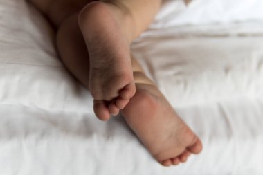 Bebek bezi takmış, beyaz yatakta yatan küçük bir kız çocuğu. Bir yaşında beyaz bir çocuğun tombul bacakları. Çocuk beşiğinde uyuyor. ev, konfor, çocukluk, bakım, aşk, tatlı rüya konsepti