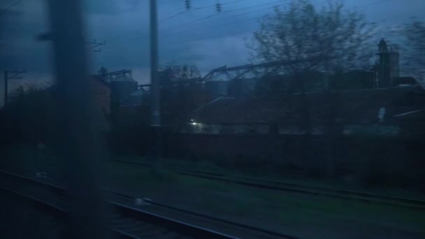 Yüksek hızlı trenin penceresinden eski paslı yük vagonlarının manzarası ve yaz arkaplanındaki güzel bulutlu gökyüzü üzerindeki çelik tahıl siloları. Ulaşım, seyahat, demiryolu, yol, zina kavramı — Stok video