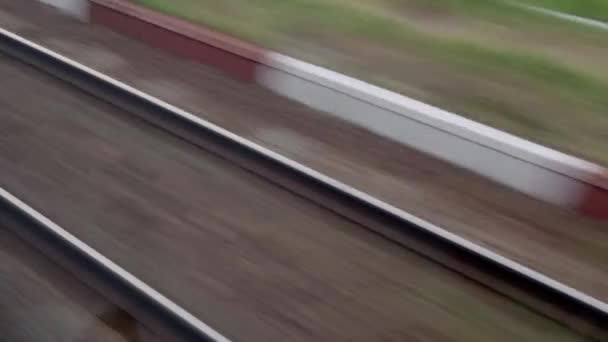 Vista dalla finestra di treno di velocità con abbagliamento su vetro e binari paralleli su paesaggio di prati e foresta prima del tramonto sullo sfondo estivo. Trasporto, viaggio, strada, ferrovia, concetto di comnicazione — Video Stock