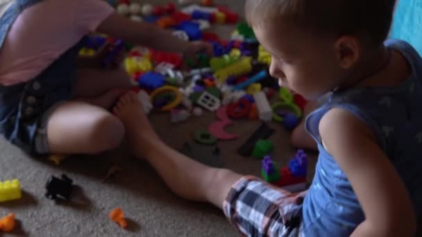 Pequenos irmãos pré-escolares crianças sentadas no chão com brinquedos na sala de crianças. Os rapazes estão a brincar com o construtor na sala de jogos. As crianças passaram um tempo divertido em casa. Infância, amizade, conceito de desenvolvimento — Vídeo de Stock