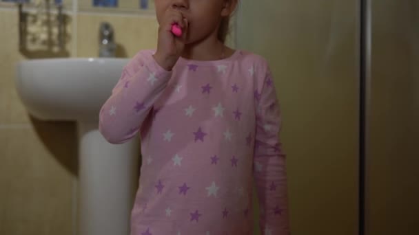 Portret szczęśliwy ładny młody przedszkolak dziewczyna na piżamie mycia zębów i patrząc na aparat fotograficzny w łazience. Codzienna opieka zdrowotna dziecka. Biała dziewczyna myjąca się w domu. Styl życia, koncepcja dzieciństwa — Wideo stockowe