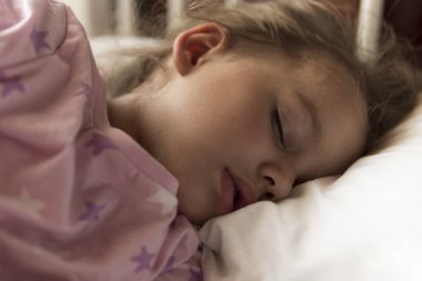 Şirin, neşeli, 3-4 yaş arası, kreş çocuğu öğle yemeği arasında evinde yastıklı pembe pijamayla beyaz beşikte tatlı tatlı uyuyor. Çocukluk, rahatlık, rahatlık, ilaç, sağlık konsepti