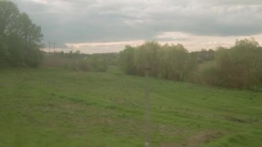 Yüksek hızlı trenin penceresinden manzarası güzel doğa manzarası vahşi arazi ve orman akşam bulutlu gökyüzü günbatımı yaz arkaplanında. Ulaşım, seyahat, demiryolu, iletişim konsepti