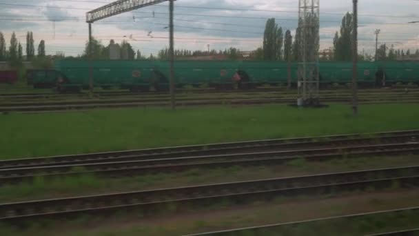 View from window of high-speed train on landscape of old rusty boxcars and high brick chimney on beautiful cloudy blue sky in summer background. Transport, travel, railway, road, comnication concept — Stock Video