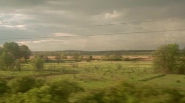 Yüksek hızlı trenin penceresinden manzarası güzel doğa manzarası vahşi arazi ve orman akşam bulutlu gökyüzü günbatımı yaz arkaplanında. Ulaşım, seyahat, demiryolu, iletişim konsepti