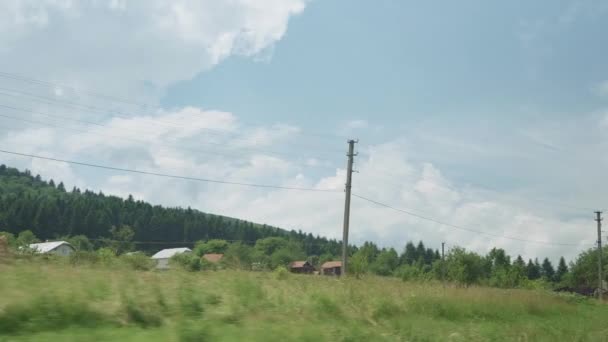 Vue depuis la fenêtre du train à grande vitesse sur le paysage de la belle nature champ sauvage et forêt de montagnes par temps nuageux propre ensoleillé en arrière-plan d'été. Transport, voyage, chemin de fer, concept de communication — Video