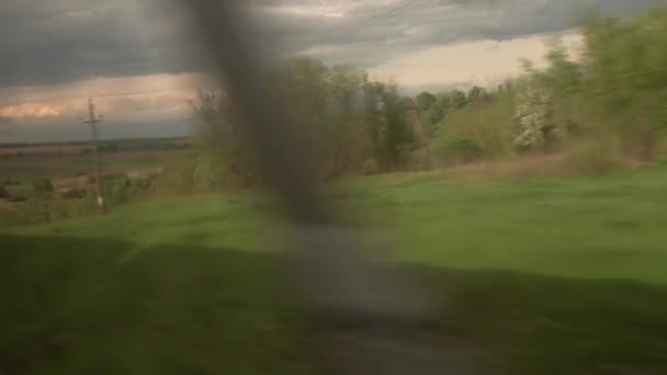 Uitzicht vanuit raam van sneltrein met verblinding op glas op prachtig landschap van weide en bos bewolkte hemel zonsondergang in de zomer natuur achtergrond. Vervoer, vervoer, weg, spoor, hoererij — Stockvideo