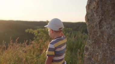 İki yaban domuzu kız ve erkek gün batımından önce dağın tepesinde uzun otların arasında bir şey bulurlar. Çayırdaki çocuk. Dağlarda mutlu bir çocuk. Çocukluk, doğa, yaşam tarzı, yaz konsepti