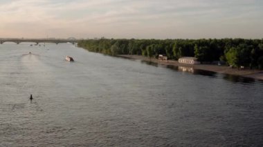 Panorama Top Aerial manzaralı balıkçı teknesi okyanusu hareket ediyor. Gün batımında Dnipro nehrinde balıkçıyla motorlu tekne gezintisi. Şehirdeki göllerin üzerindeki köprü manzarası. Su taşımacılığı, seyahat, yaz