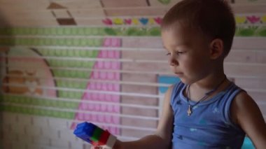 Küçük anaokulu çocukları yerde ellerinde oyuncaklarla çocuk odasında oturuyorlar. Çocuklar oyun odasında inşaatçıyla oynuyorlar. Çocuklar evlerinde eğleniyorlar. Çocukluk, arkadaşlık, kalkınma kavramı