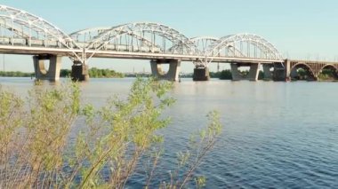 Gün batımında Dnipro nehrinde yüzen balıkçı teknesinin manzarası. Şehirdeki göl üzerindeki sanayi köprüsünün manzarası. Tren ve ovalar güneşli yaz günlerinde göletin üzerinden geçer. Su taşır, seyahat eder.