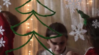 Otantik sevimli bir anne ve iki küçük anaokulu öğrencisi kız ve erkek kardeş 2-4 yaşlarında pencereye Noel ağacı çiziyor. Çocuklu genç bir kadın kar taneleri yapıştırıyor. Xmas, yeni yıl, kış konsepti.